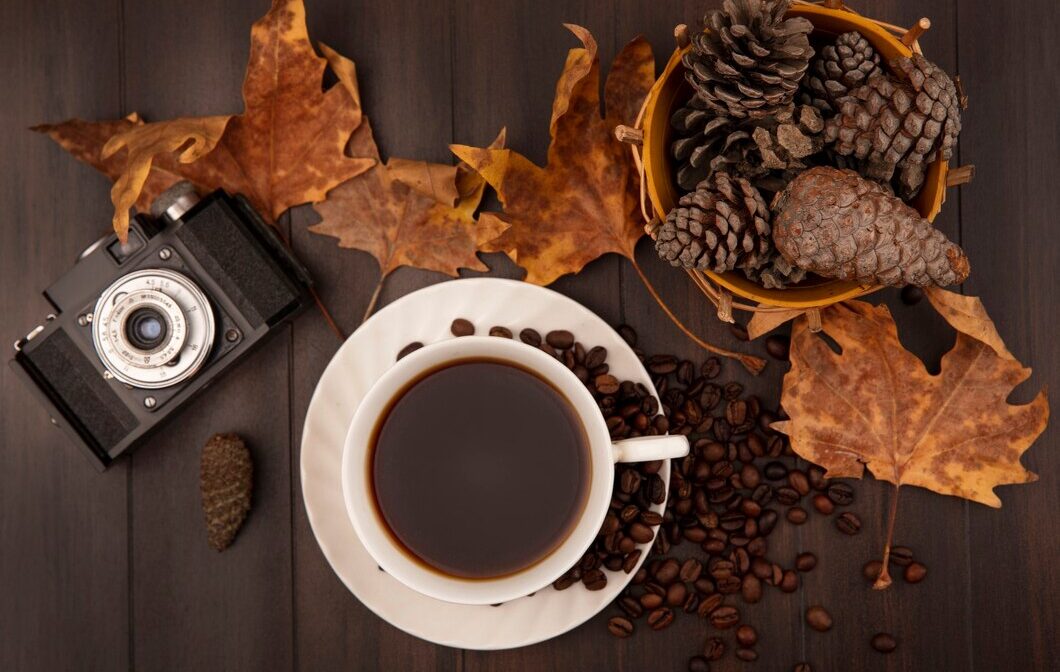 top-view-cup-coffee-with-pine-cones-bucket-with-golden-yellow-leaves-coffee-beans-isolated-wooden-wall_141793-76023